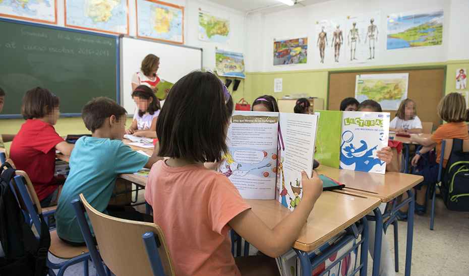 Varios niños leen sus libros de texto en un aula de Primaria.