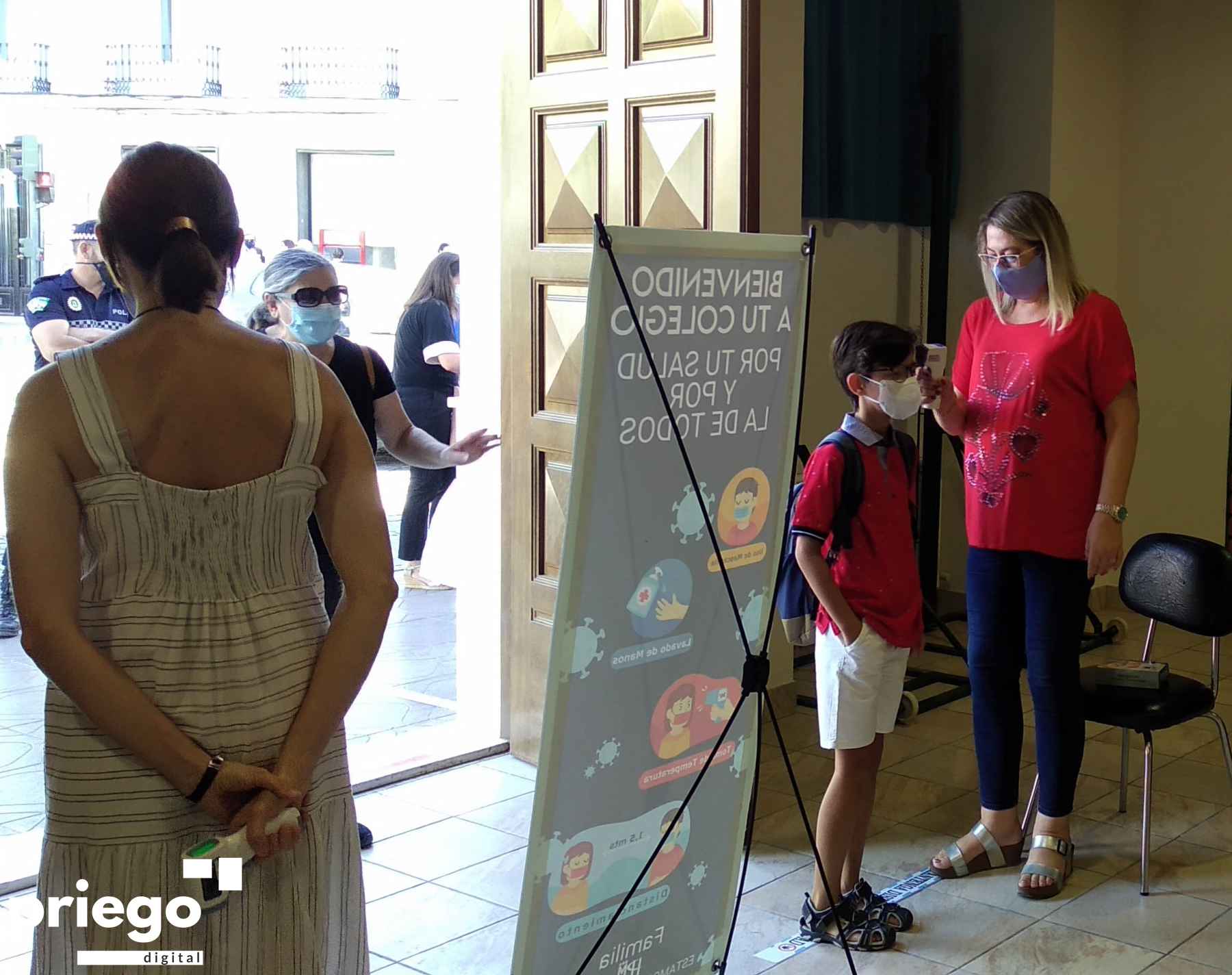 Una profesora toma la temperatura a un alumnos en el acceso al colegio Ntra. Señora de las Angustias.