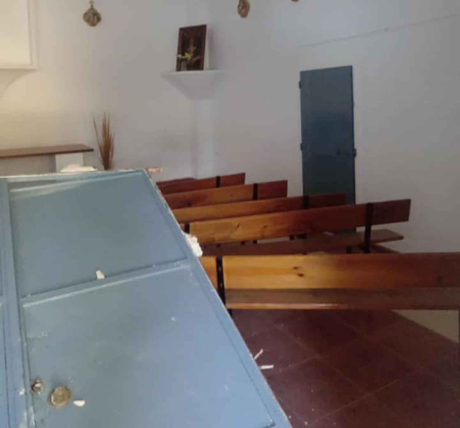 Interior de la ermita con la puerta destrozada en primer término.
