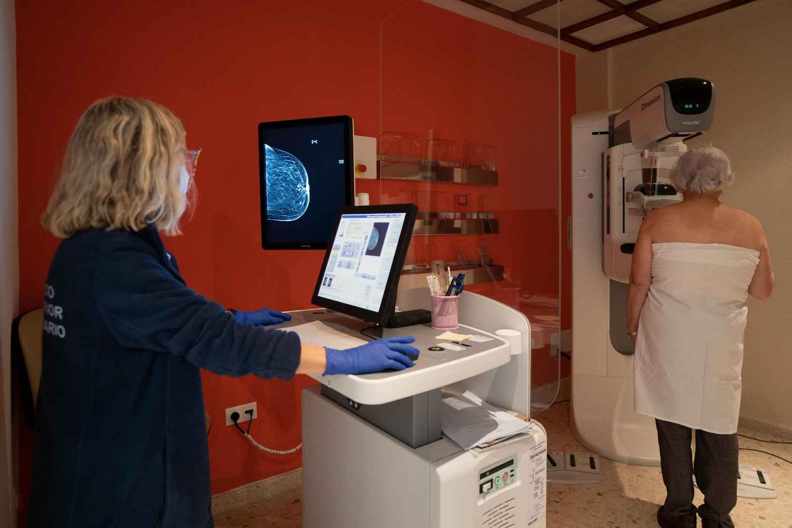 Una profesional sanitaria realiza una mamografía a una paciente.